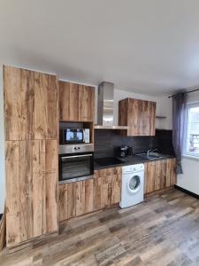 eine Küche mit Holzschränken, einer Waschmaschine und einem Trockner in der Unterkunft Gîte Au Coin du Chêne in Lembach