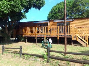 a wooden cabin with a porch and a fence at Anerley Garden Park Resort in Port Shepstone