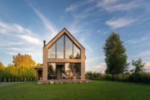 una pequeña casa con ventanas de cristal en el césped en Hytte Na Wyspie -,,Roztoczańskie Morze'', en Kulików