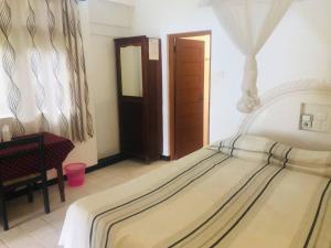 a bedroom with a bed and a chair and a mirror at Hotel Hemadan in Bentota