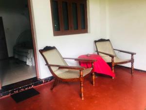 two chairs with a red table in a room at Hotel Hemadan in Bentota