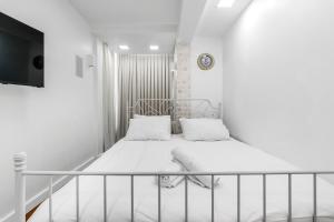 a small white room with a bed and a tv at Brown suite in Tel Aviv
