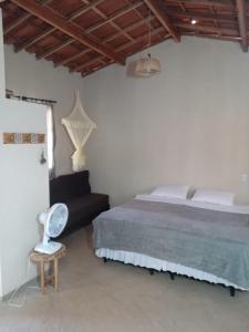 ein Schlafzimmer mit einem Bett, einem Stuhl und einem Ventilator in der Unterkunft Vila Sincorá - Chalé para 4 pessoas com cozinha a 2 km da portaria da Cachoeira do Buracão in Ibicoara