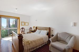 - une chambre avec un lit, une chaise et une fenêtre dans l'établissement Villa do Bosque, à Guilhabreu