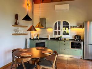 a kitchen with a table and chairs and a refrigerator at Blooming Botanic Houses in Estreito da Calheta
