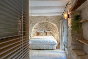 a bedroom with a bed in a stone wall at La Grange de la Chèvre d'Or in Lagnes +26 photos