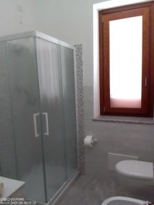 bagno con doccia in vetro e servizi igienici di Appartamento B di Vico Martiri a Teulada