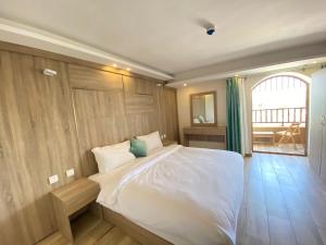 Castle beach hotel في العقبة: غرفة نوم بسرير ابيض وبجدار خشبي