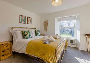 a bedroom with a bed with yellow sheets and a window at Helebridge House in Marhamchurch