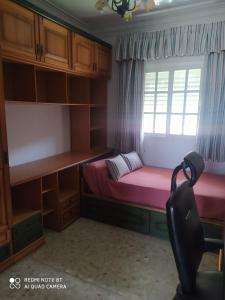 Un pequeño dormitorio con una cama rosa y una ventana en CHALET VACACIONAL a 10 minutos de la playa de La Barrosa, en Chiclana de la Frontera