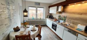 eine Küche mit einem Tisch und einem Waschbecken sowie einem Tisch und Stühlen in der Unterkunft Gästehaus Zur alten Post in Dornumersiel + 92 Fotos