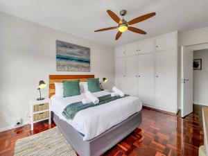 a bedroom with a large bed with a ceiling fan at Charming and Sunny Apartment in Cape Town