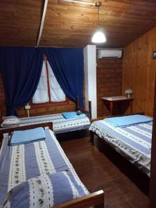 a room with two beds and a blue curtain at La casona in Puerto Iguazú