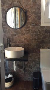 a bathroom with a sink and a mirror on a stone wall at Villa sunset Antigoni in Kallirákhi