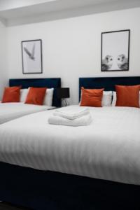 a bedroom with two beds with orange and white pillows at Water Street by Ustay Aparthotels in Liverpool