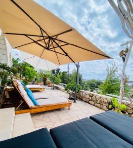 a patio with an umbrella and a bench and a table at Villa Marijam in Hvar