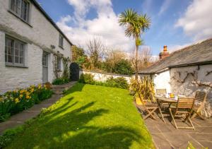 a garden with a table and chairs and a house at Rose Cottage in Helford