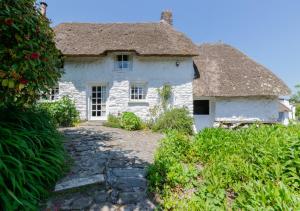 Cette ancienne maison en pierre est dotée d'un toit de chaume. dans l'établissement Mimosa, à Helford