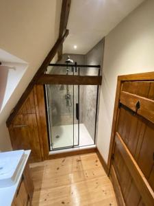 een badkamer met een douche en een glazen deur bij A newly renovated, cosy escape in the beautiful Shepherd's Cottage in East Dereham