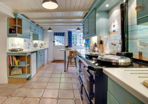 a kitchen with blue cabinets and a stove top oven at Well Too in Helford