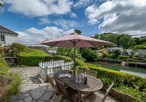 a wooden table with an umbrella on a patio at Well Too in Helford