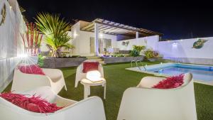 einen Hinterhof mit Stühlen und einen Swimmingpool in der Nacht in der Unterkunft Villa Amatista Salinas Golf & Beach in Caleta de Fuste + 37 Fotos