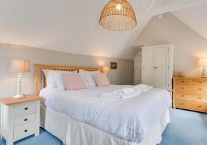 a bedroom with a large white bed and a lamp at Well Too in Helford