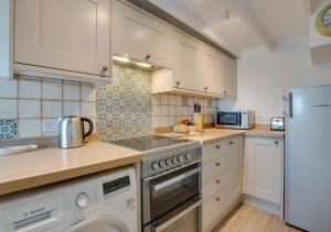 a kitchen with white cabinets and a white refrigerator at Kelynack in Porthleven