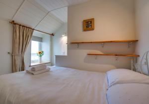 a bedroom with a large white bed with a window at Kelynack in Porthleven