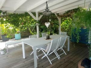 una mesa blanca y sillas en una terraza de madera en Villa Cocon Bleu , plage à pied ! en Sainte-Luce