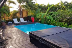 a swimming pool with two white chairs next to it at Villa Cocon Bleu , plage à pied ! in Sainte-Luce