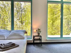 ein Schlafzimmer mit einem Bett und zwei großen Fenstern in der Unterkunft Project Bay - Workation / CoWorking in Lietzow