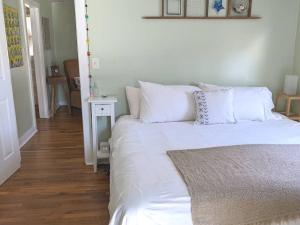 a bedroom with a bed with white sheets and pillows at Victory Garden Cottage 12 min to downtown with fire pit and in Asheville