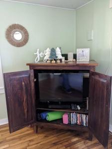 a wooden entertainment center with a flat screen tv at Victory Garden Cottage 12 min to downtown with fire pit and in Asheville