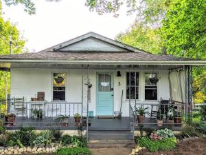 una pequeña casa blanca con una puerta azul en Victory Garden Cottage 12 min to downtown with fire pit and en Asheville