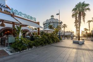 a street with cafes and palm trees and a building at Parque Santiago III Official in Playa de las Americas
