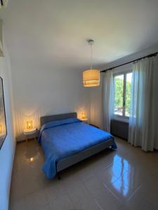 een slaapkamer met een blauw bed en een raam bij Casa Enza: appartamento a un passo dal mare. in Bordighera