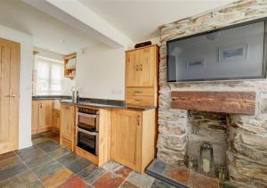 cocina con chimenea de piedra y TV de pantalla plana en 4 Seaview en Looe