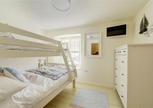 biała sypialnia z łóżkiem piętrowym i telewizorem w obiekcie 4 Seaview w Looe