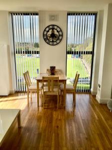 una sala da pranzo con tavolo, sedie e orologio di Castle Quarter Apartment with Free on site Parking a Bedford