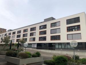 a large white building with windows on a street at One bedroom 3pieces entire Modern Appartment close to Airport, CERN, Palexpo, public transport to the center of Geneva in Meyrin