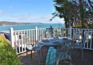 een tafel en stoelen op een terras met uitzicht op de oceaan bij Dawn End in Looe