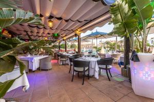 a restaurant with white tables and chairs and plants at Parque Santiago III Official in Playa de las Americas