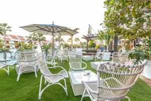 a group of white chairs and tables with an umbrella at Parque Santiago III Official in Playa de las Americas