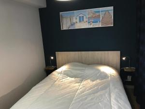 een slaapkamer met een wit bed met een foto aan de muur bij Appartement Longeville-sur-Mer, 2 pièces, 4 personnes - FR-1-336-69 in Longeville-sur-Mer