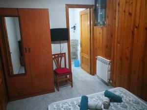 1 dormitorio con cama, silla y espejo en Hostal Escarla, en Aren