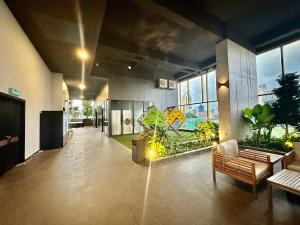 um átrio de escritório com bancos, plantas e janelas em Millennium Suite At Opus Residence em Kuala Lumpur