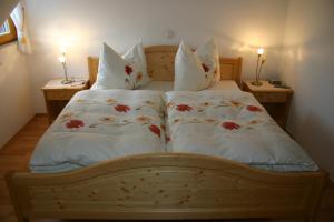 ein Bett mit weißer Bettwäsche und roten Blumen darauf in der Unterkunft Apfelhof FLIEDER in Kukmirn