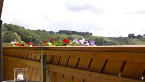 a wooden fence with flowers on it with a glass at Apfelhof FLIEDER in Kukmirn