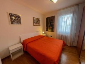 a bedroom with a orange bed and a window at Trilocale vista mare con 2 bagni nel centro storico - Agenzia Cocal in Caorle